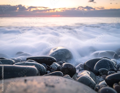 A serene seascape with waves crashing over smooth rocks at sunset