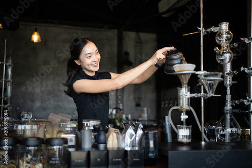 Tableau sur toile Happy young Asian barista skillfully brews specialty coffee using a gooseneck ke