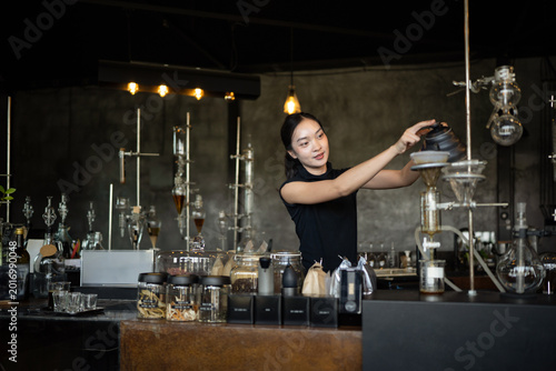 Obraz na plátně Happy young Asian barista skillfully brews specialty coffee using a gooseneck ke