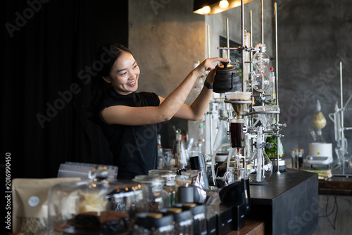 Foto Happy young Asian barista skillfully brews specialty coffee using a gooseneck ke