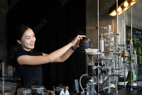 Foto Happy young Asian barista skillfully brews specialty coffee using a gooseneck ke