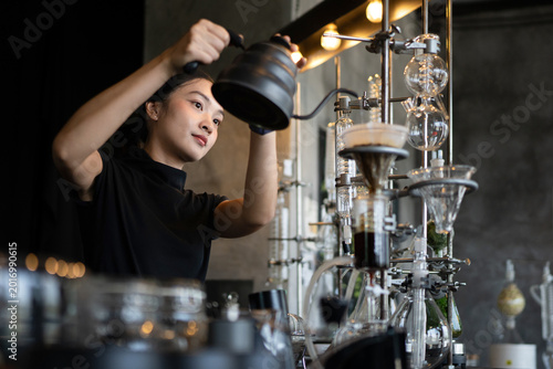 Fotografie Happy young Asian barista skillfully brews specialty coffee using a gooseneck ke