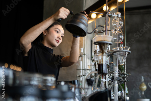 Fotografija Happy young Asian barista skillfully brews specialty coffee using a gooseneck ke