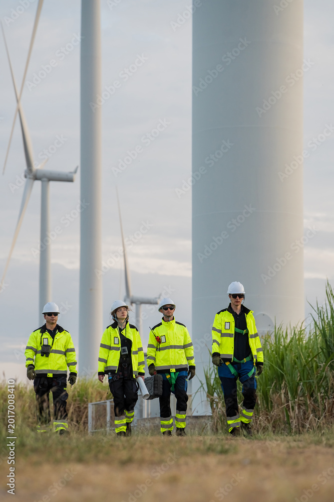 Fototapeta premium Team of professional engineers walking and inspecting wind turbine farm for renewable energy development.