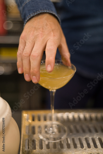 Elegant and sophisticated cocktail served on a professional bar counter. The image features a beautifully garnished drink in a stylish glass, set against a background of blurred liquor bottles