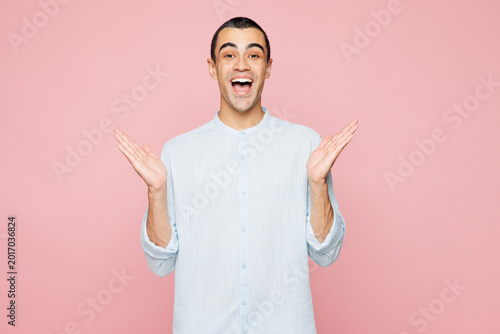 Foto Young shocked surprised excited amazed happy middle eastern man he wear casual blue cotton shirt look camera spread hands isolated on plain pastel light pink wall background studio