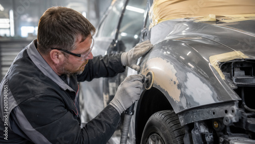 Auto Body Technician Sanding Damaged Car Panel