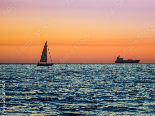 Sailboat and cargo ship at sunset in Martigues