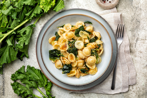 Top view of pasta Orecchiette con le cime di rapa, popular in Southern Italy dish, typical of Apulia. Made with anchovy, bread crumbs and rapini, also called broccoli rabe or turnip greens.