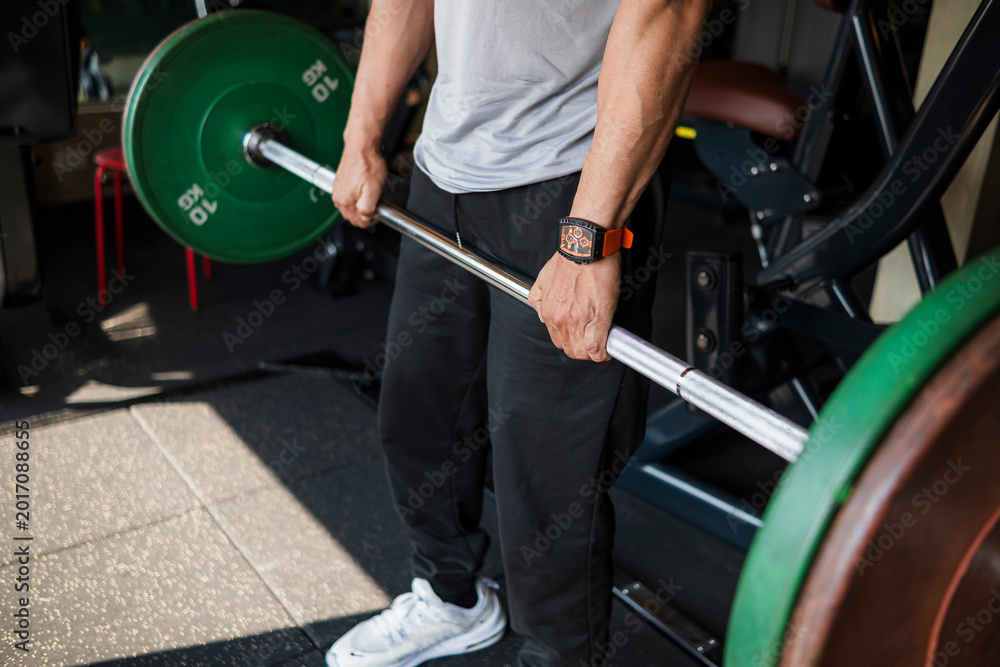 Fototapeta premium Close-up of an anonymous athlete performing a deadlift with a double overhand grip to build strength and improve lifting form