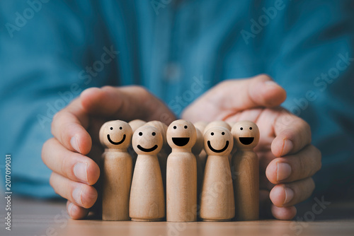 Customer relationship management concept with wooden people figures protected by human hands, representing customer care, client satisfaction, loyalty, support service and business trust building
