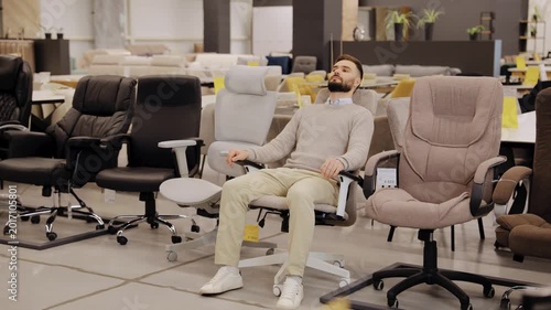 Bearded man relaxing in ergonomic office chair, finding ultimate comfort in furniture showroom