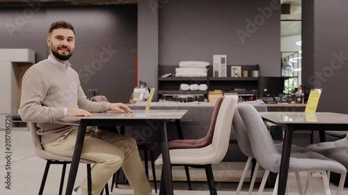 Man choosing new elegant dining table and chairs in modern furniture store interior, designing home decor