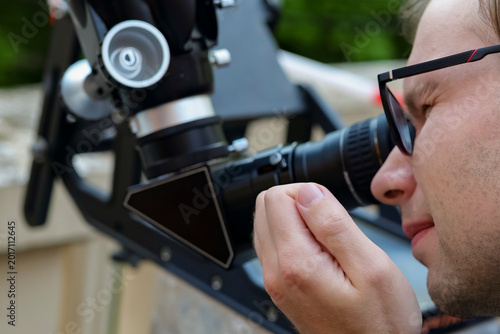 Fotografía Person looking through an astronomical telescope eyepiece in a close up view, demonstrating amateur astronomy equipment in use