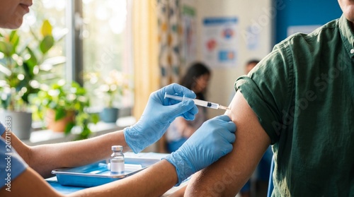 Woman nurse in blue scrubs administering vaccine injection into mans arm in clinic. Public health service with medical equipment on tray