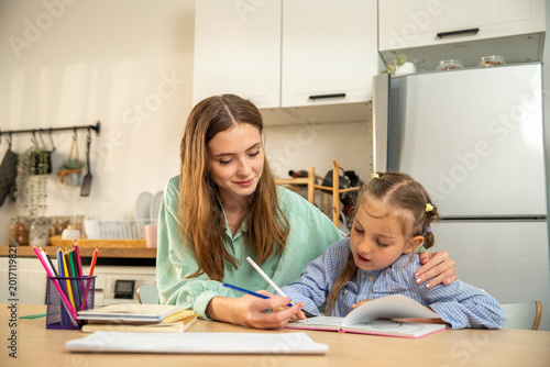 Mother helping child with homework. Mother and daughter painting together at home. Creative family activity concept. Art and bonding. Learning through creativity. 