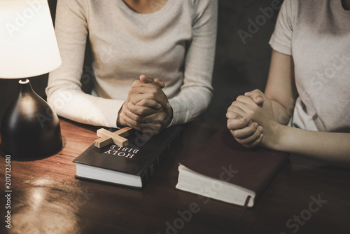 Obraz na płótnie Christian group of people holding hands praying worships together to believe and Bible on wooden table for devotional for prayer meeting