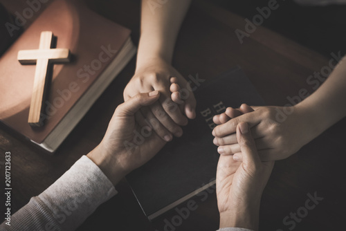 Fotografija Christian group of people holding hands praying worships together to believe and Bible on wooden table for devotional for prayer meeting
