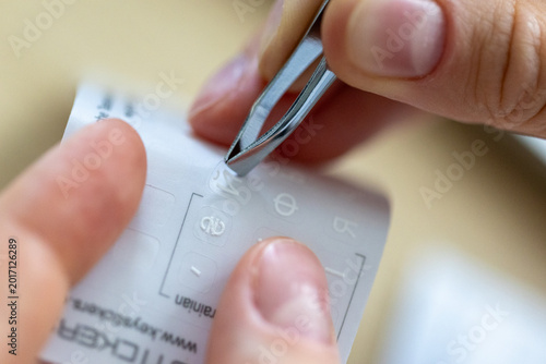 Hands taking and applying letter stickers with tweezers on English keyboard, Cyrillic alphabet characters for multilingual typing