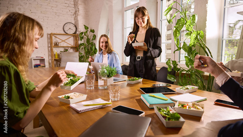 Fotografie Coworkers enjoying healthy lunch together at office table with laptops