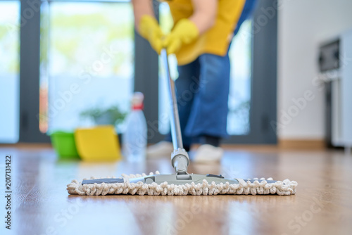 Photos Housekeeping, cleaning and woman maid with a mop cleans the living room floor at a office or workplace