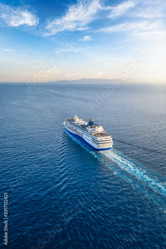 Obraz na płótnie Aerial view of a generic cruise ship sailing into the sunset over blue ocean wit