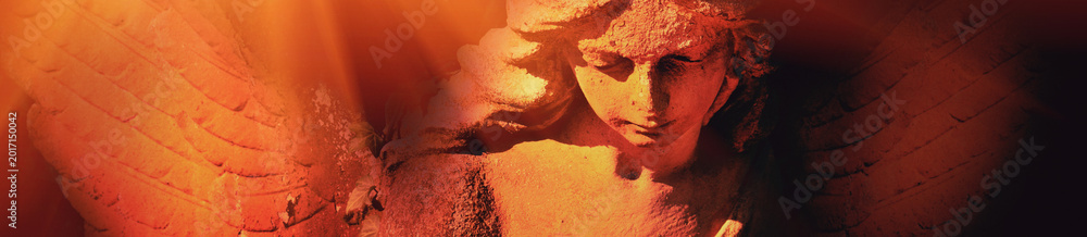 Fototapeta premium Dramatic angel statue illuminated by fiery orange light with copy space