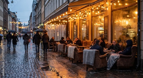 European city evening: warm string lights glow over a cozy outdoor cafe with patrons on a wet cobblestone street, pedestrians pass with umbrellas.
