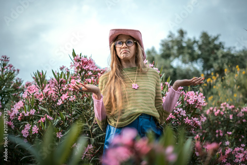 Foto Woman shrugging with hesitant expression in a flower garden, questioning a decis