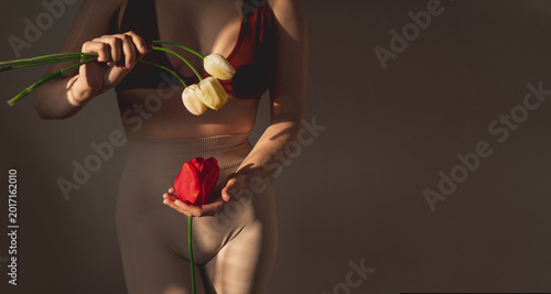 Schilderij op canvas Woman holds red tulip flower, symbol of femininity and fertility