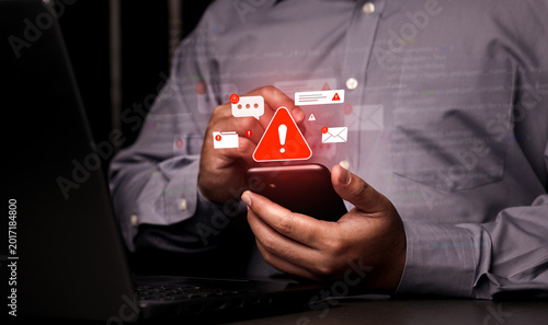 Принти на полотні A close-up of a person using a mobile phone surrounded by warning symbols, representing mobile banking fraud, SMS phishing (smishing), and online security threats in the 2026 digital era