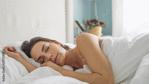 Young woman napping peacefully in cozy home bedroom during daytime. Concept relaxation and healthy routine.
