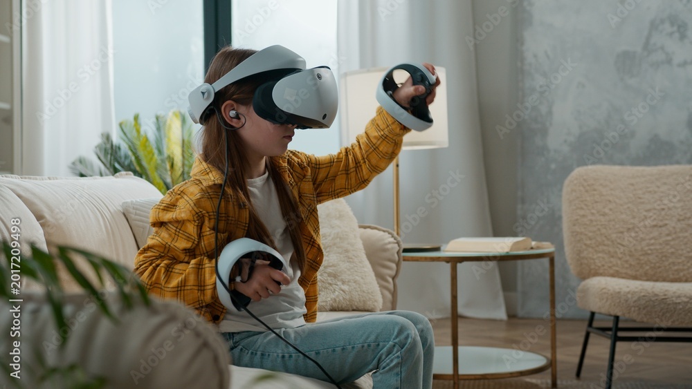 Αυτοκόλλητο Little schoolgirl chid girl in vr helmet playing game with online technology cyb