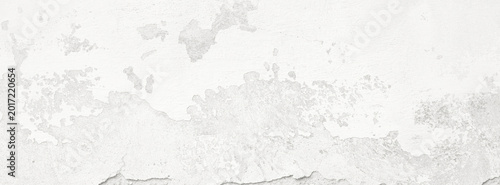 Close-up of peeling white paint texture on an aged concrete wall with weathered flaking surface