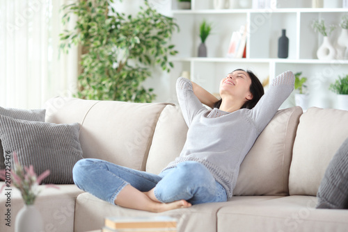 Happy asian woman relaxing on a sofa in a house