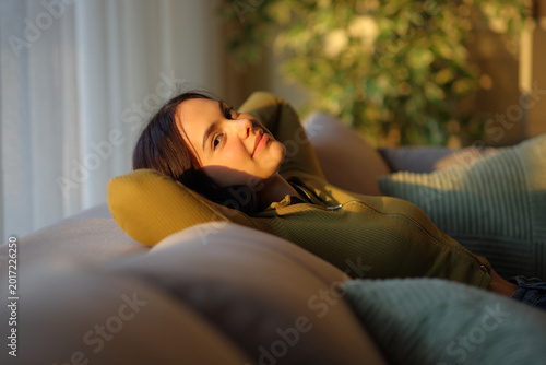 Satisfied young woman at sunset relaxing at home