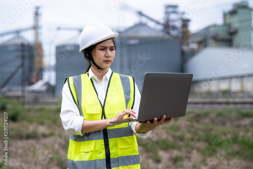 Billede på lærred Female engineer inspecting data on laptop at power plant site during workday