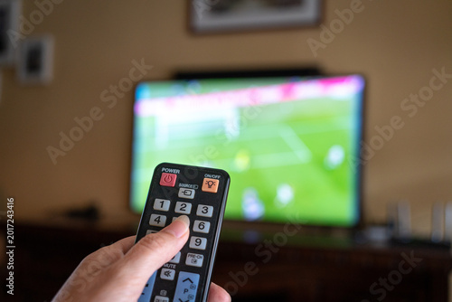 Watching football match at home, close up on remote control.