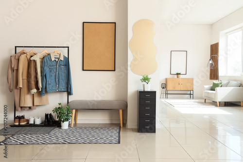 Interior of light room with mirror, soft bench and coat rack