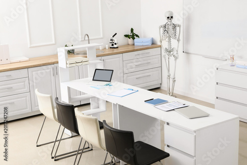 Interior of medical class with human skeleton model, whiteboard and table