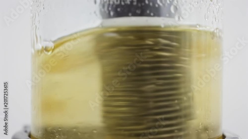 Liquid swirling inside transparent container as it is stirred, showcasing the dynamic movement and texture of the fluid in a controlled environment