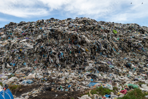 Garbage dump contains a large amount of mixed waste material with plastic and debris scattered across the area in daylight