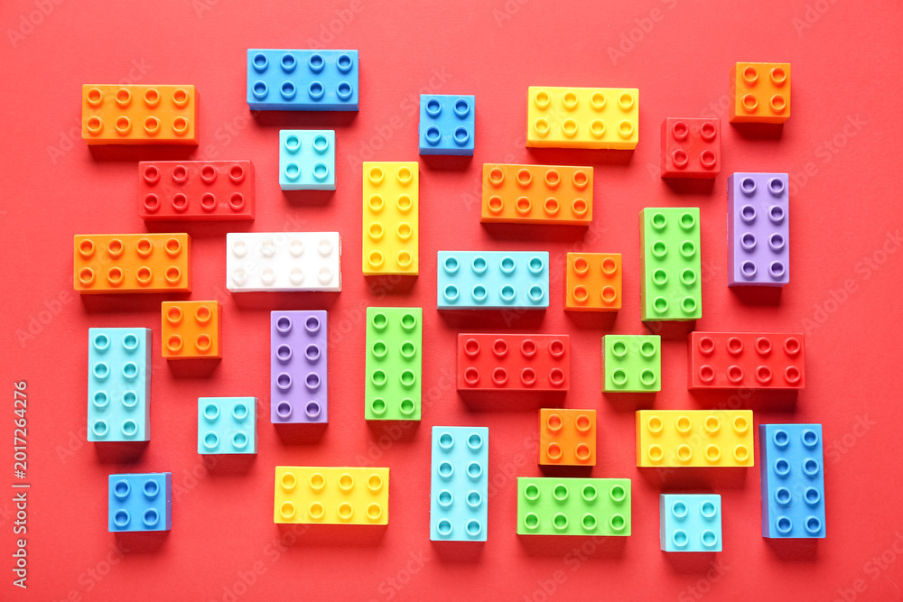 Obraz premium Colorful plastic building blocks on red background