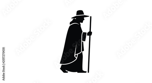 Silhouette of a man in a cloak and hat holding a staff