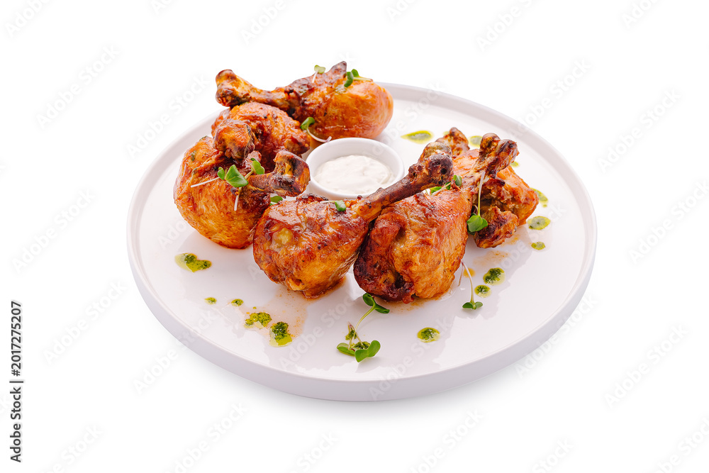 Fototapeta premium Grilled chicken pieces served with sauce on a white plate with herbs
