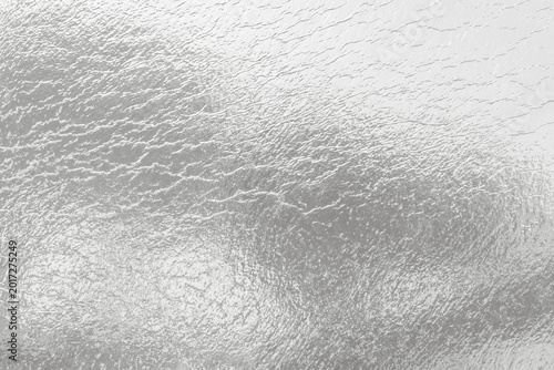 Silver metallic foil texture with abstract crinkled surface and reflective li...