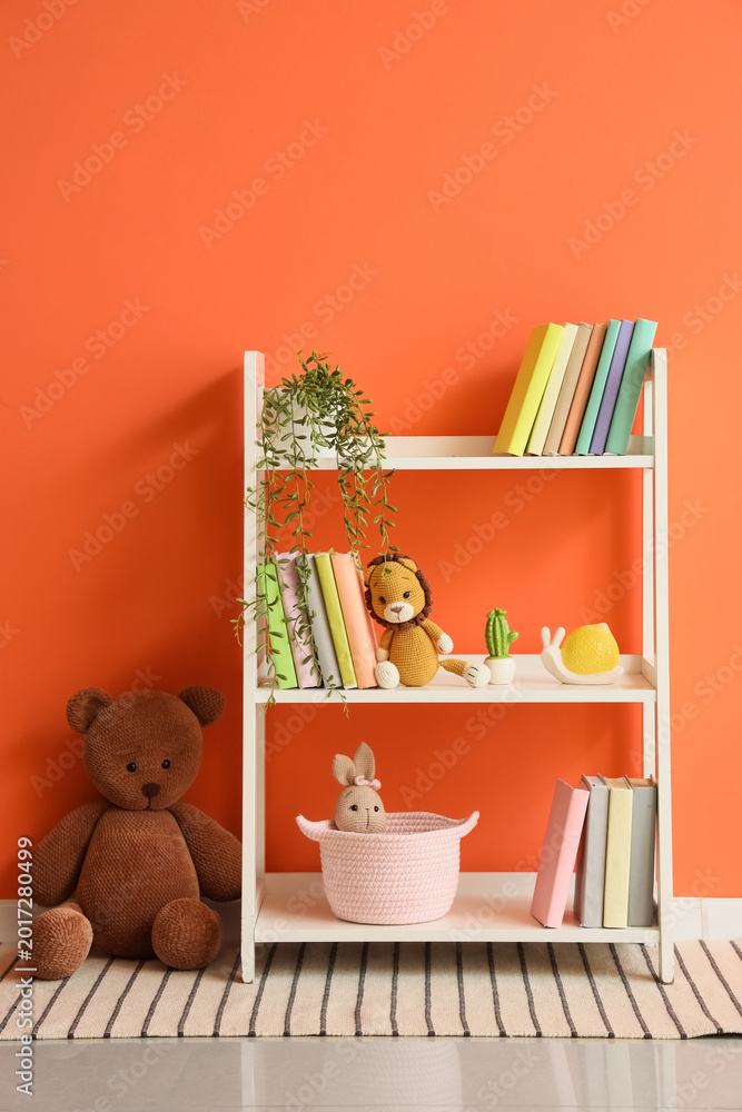 Naklejka premium Bookshelf with toys and plant near orange wall in children's room
