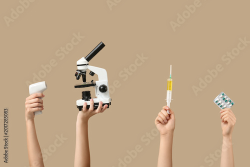 Female hands with modern microscope, pills, syringe and infrared thermometer ...