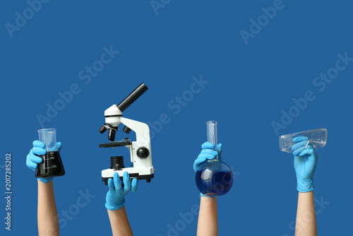 Female hands with modern microscope and laboratory glassware of samples on bl...