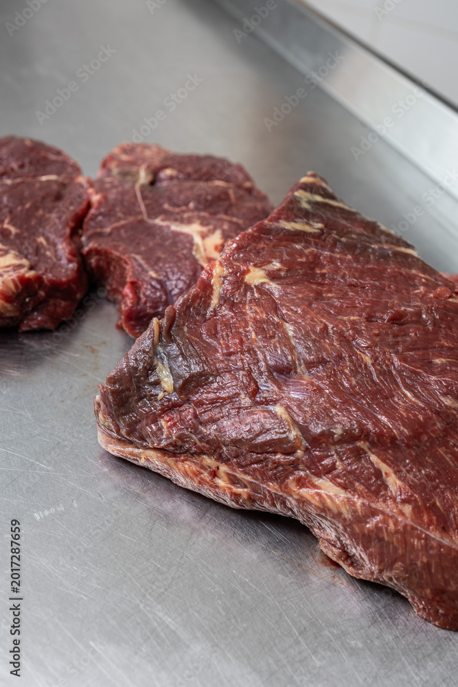 Fototapeta premium Close-up of raw beef primal cut and steaks on stainless steel